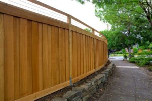 a wood privacy fence curving along a small retaining walls
